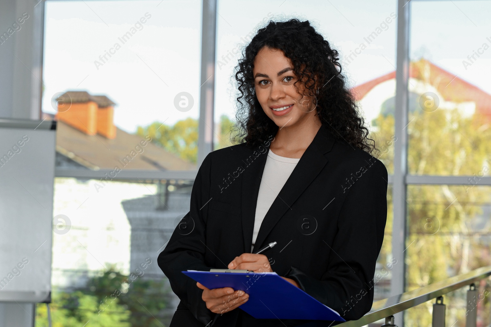 Photo of Portrait of young woman with clipboard wearing stylish suit indoors