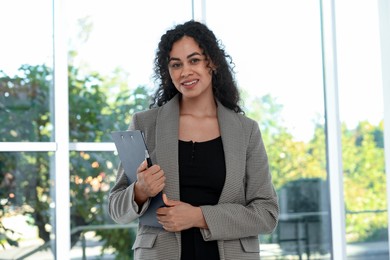 Photo of Portrait of young woman with clipboard wearing stylish suit indoors