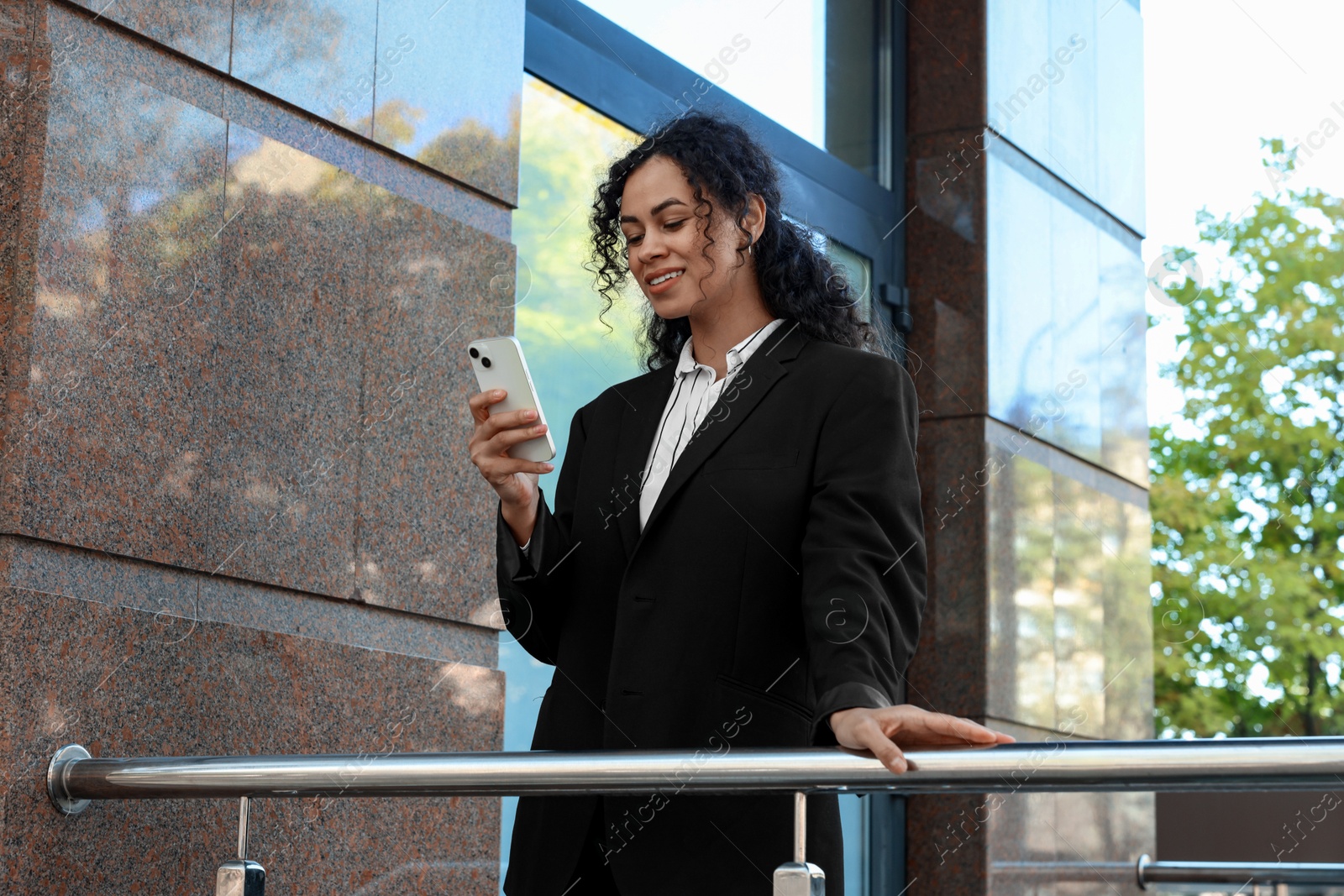 Photo of Portrait of young woman with phone wearing stylish suit outdoors