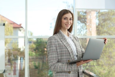 Photo of Portrait of young woman with laptop wearing stylish suit indoors