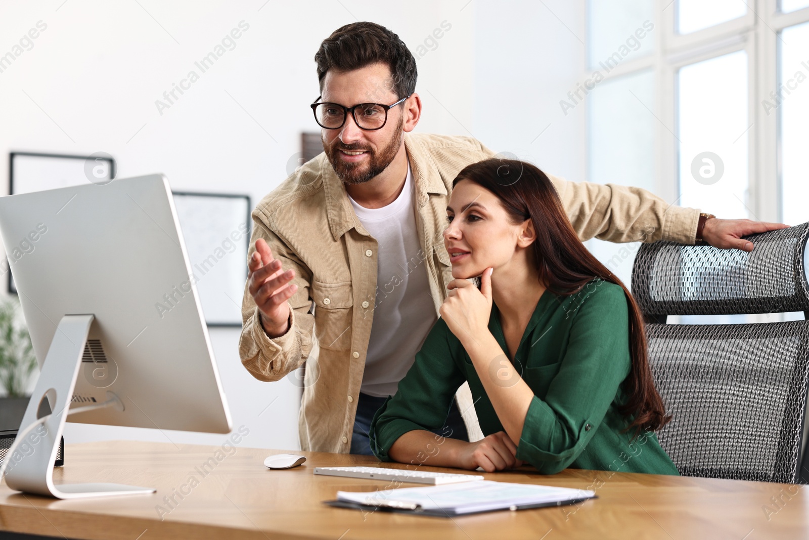 Photo of Colleagues working with computer at desk in office