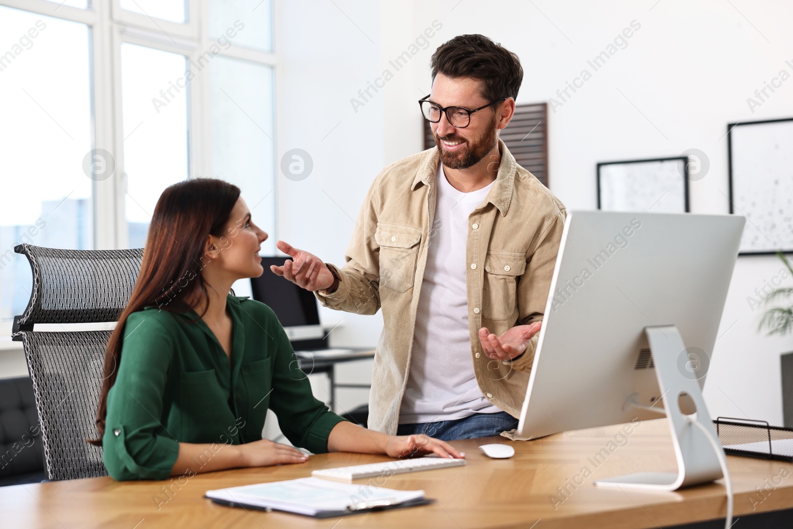 Photo of Colleagues working together at desk in office