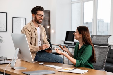 Photo of Colleagues working together at desk in office