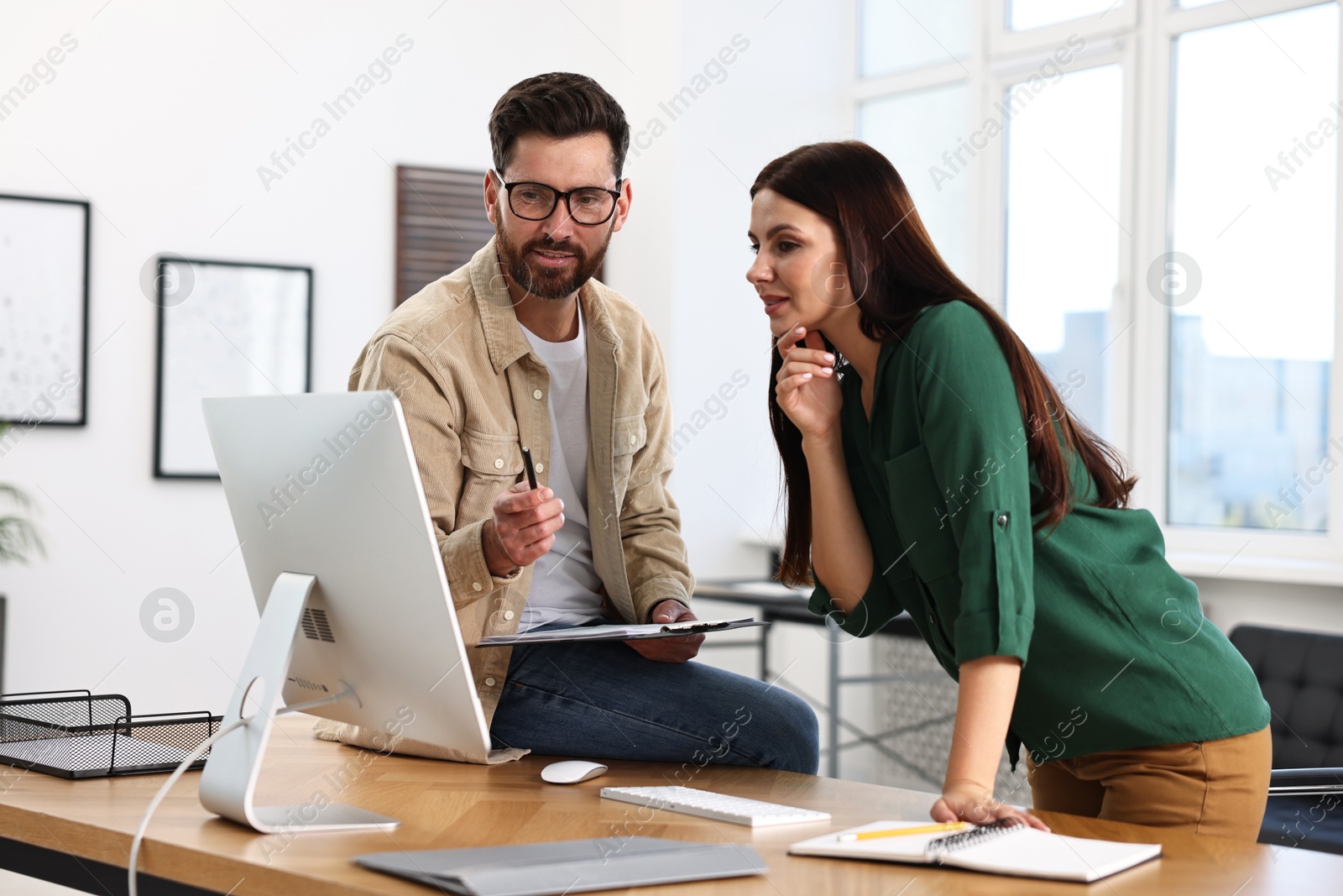 Photo of Colleagues working with computer at desk in office