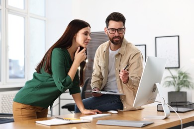 Photo of Colleagues working with computer at desk in office