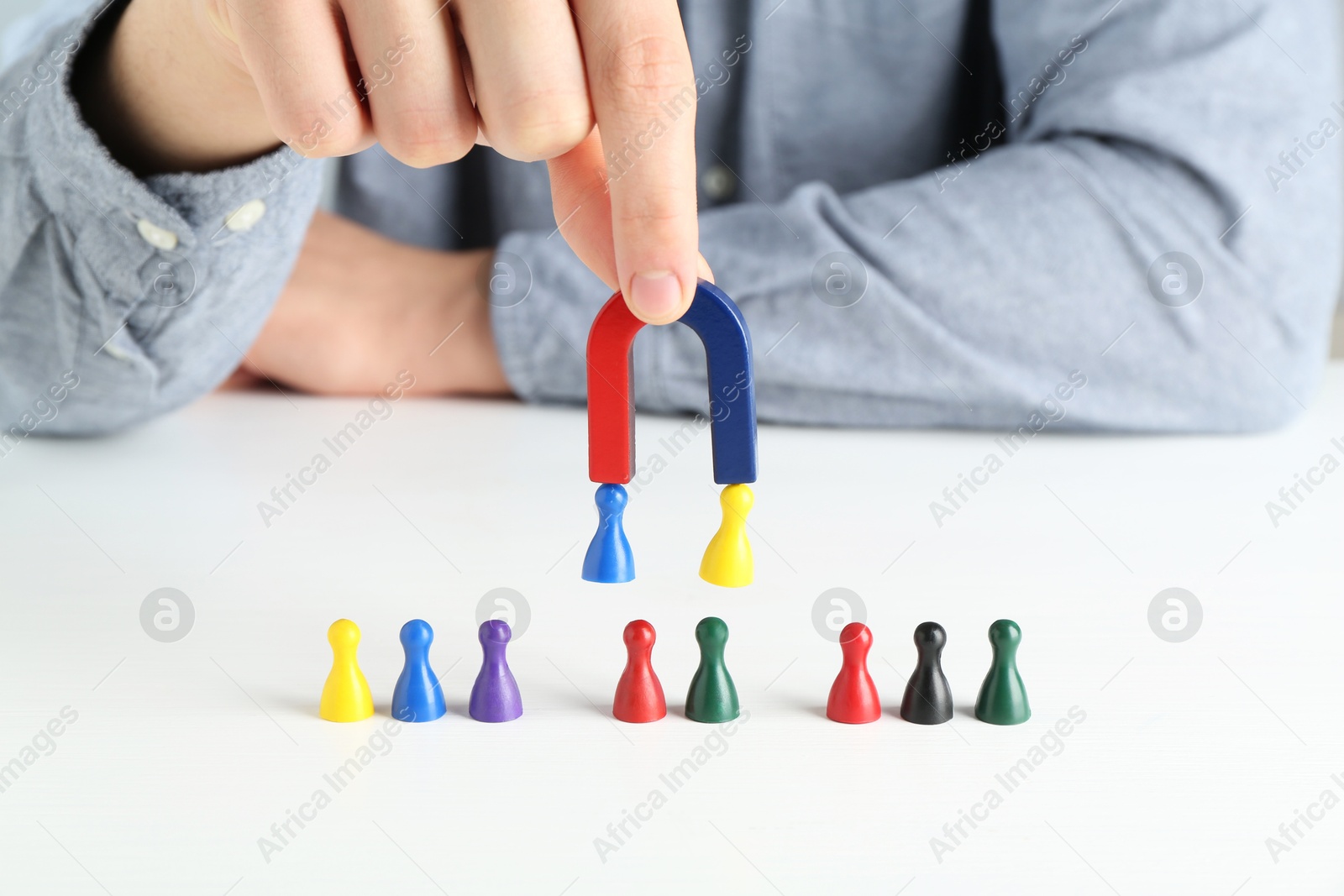 Photo of Man with magnet attracting game pieces at white table, closeup