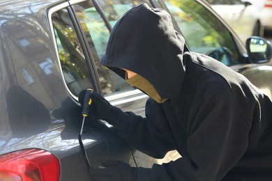 Photo of Thief with screwdriver opening fuel cap. Car hijacking