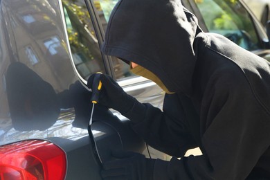 Photo of Thief with screwdriver opening fuel cap. Car hijacking