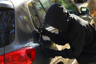 Photo of Thief with screwdriver opening fuel cap. Car hijacking