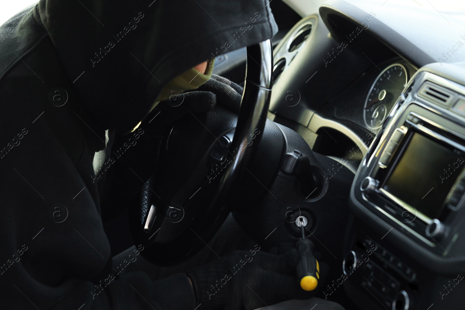 Photo of Thief trying to start ignition switch with screwdriver, closeup. Car hijacking