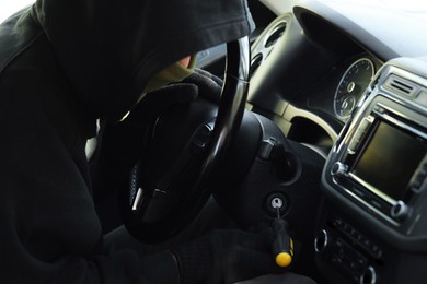 Photo of Thief trying to start ignition switch with screwdriver, closeup. Car hijacking