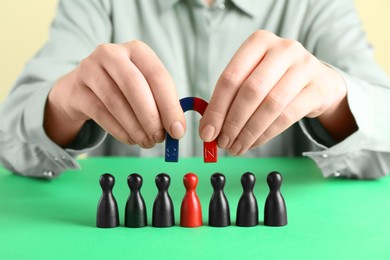 Photo of Woman with magnet attracting game pieces at green table, closeup