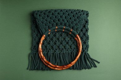 Photo of Macrame shopping bag with wooden handles on green background, top view