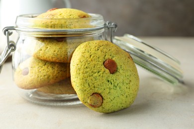 Photo of Delicious mint chocolate chip cookies in jar on light table, closeup