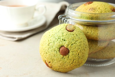 Photo of Delicious mint chocolate chip cookies in jar on light table, closeup