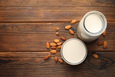 Fresh almond milk and nuts on wooden table, top view. Space for text