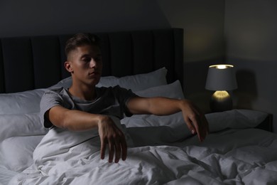 Photo of Young man suffering from sleepwalking on bed at home