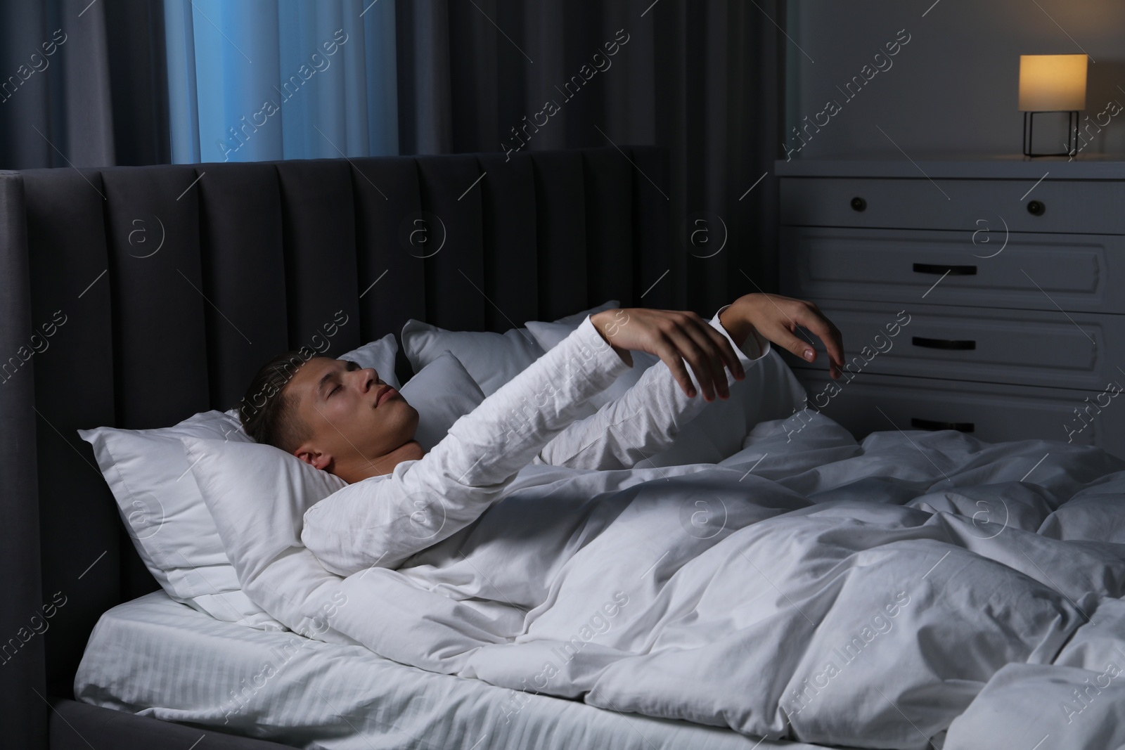 Photo of Young man suffering from sleepwalking on bed at home