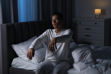 Photo of Young man suffering from sleepwalking on bed at home