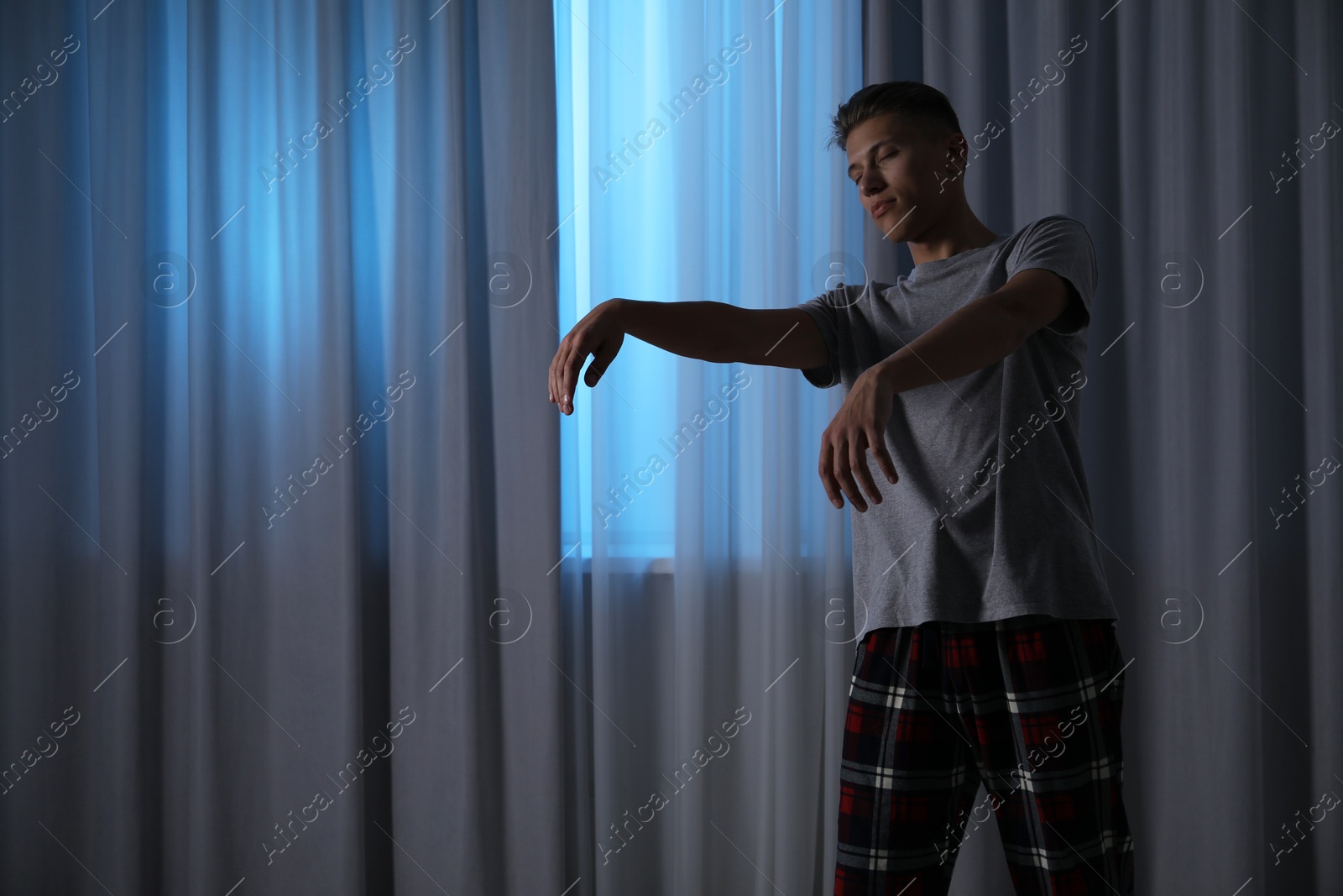 Photo of Young man suffering from sleepwalking at home, space for text