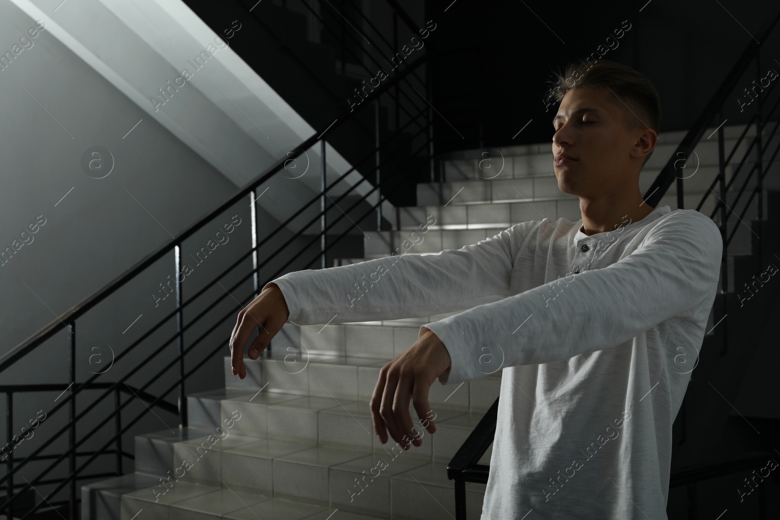 Photo of Young man suffering from sleepwalking on stairs indoors, space for text