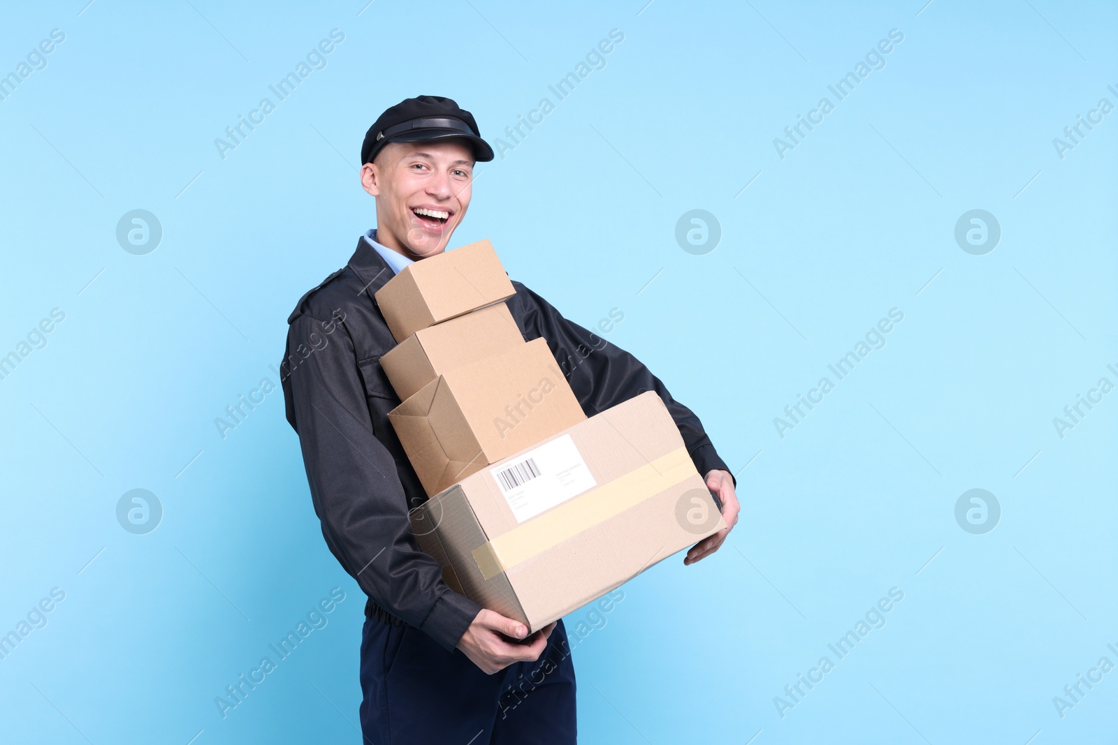 Photo of Happy postman with parcels on light blue background