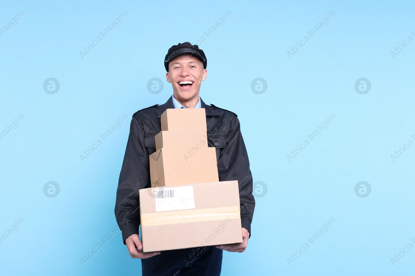 Photo of Happy postman with parcels on light blue background