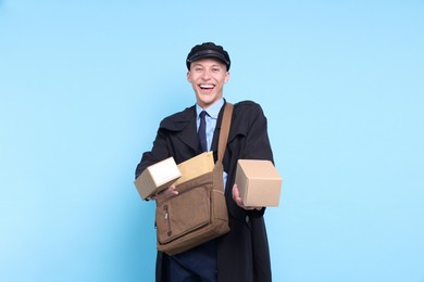 Photo of Happy postman with bag giving parcels on light blue background