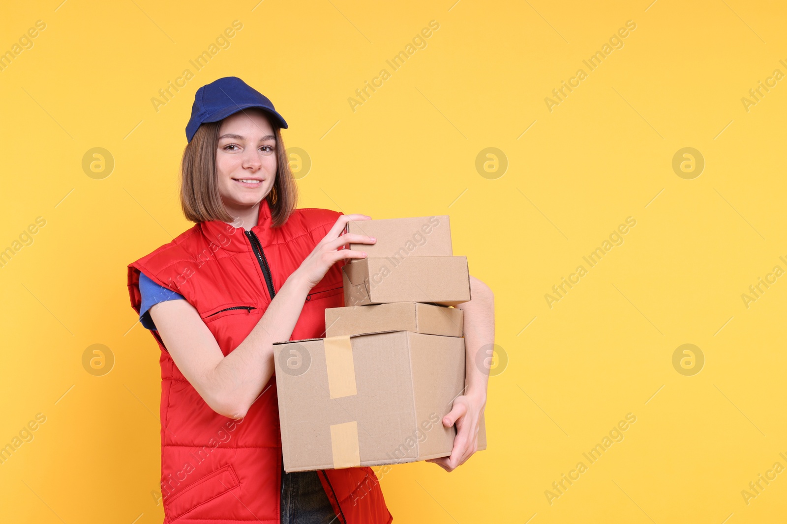 Photo of Happy postwoman with parcels on yellow background. Space for text