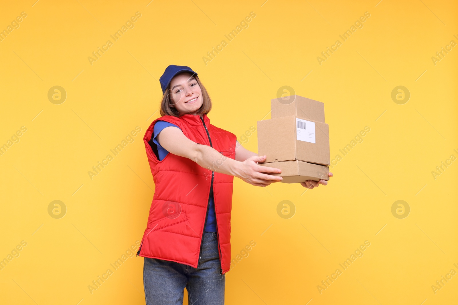 Photo of Happy postwoman with parcels on yellow background