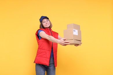 Photo of Happy postwoman with parcels on yellow background