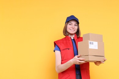 Photo of Happy postwoman with parcels on yellow background