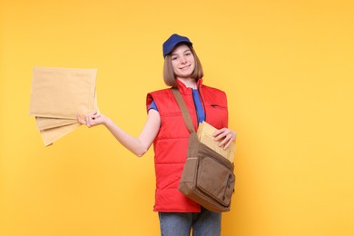 Photo of Happy postwoman with bag and envelopes on yellow background