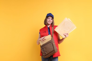 Photo of Happy postwoman with bag and envelopes on yellow background. Space for text