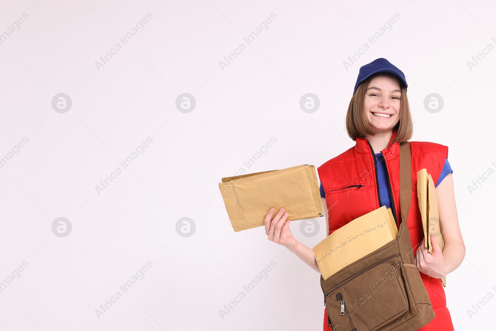 Photo of Happy postwoman with bag and envelopes on white background. Space for text