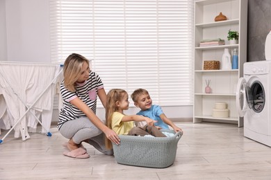 Happy housewife and her kids playing together in laundry room