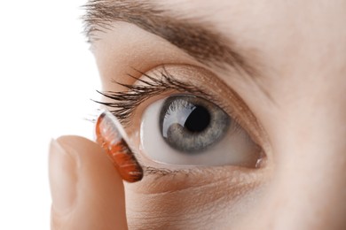 Photo of Woman putting in red color contact lens on white background, closeup