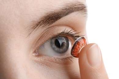 Photo of Woman putting in red color contact lens on white background, closeup