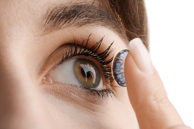 Woman putting in blue color contact lens on white background, closeup