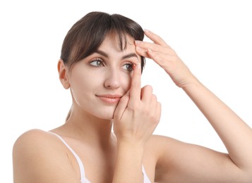 Photo of Young woman putting in red color contact lens on white background