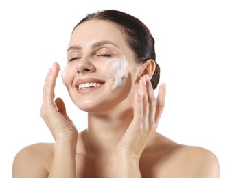 Smiling woman washing her face with cleansing foam on white background