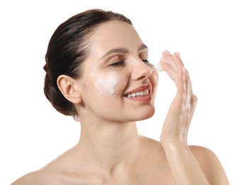 Smiling woman washing her face with cleansing foam on white background