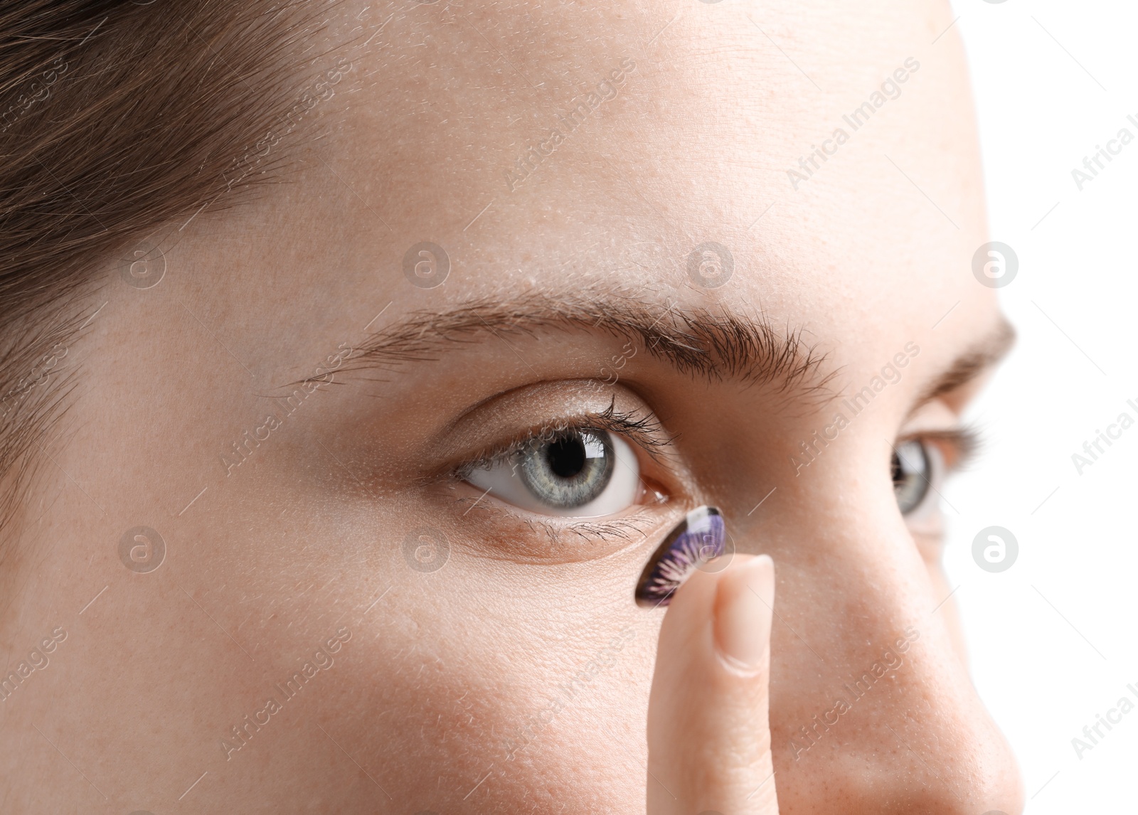 Photo of Woman putting in color contact lens on grey background, closeup