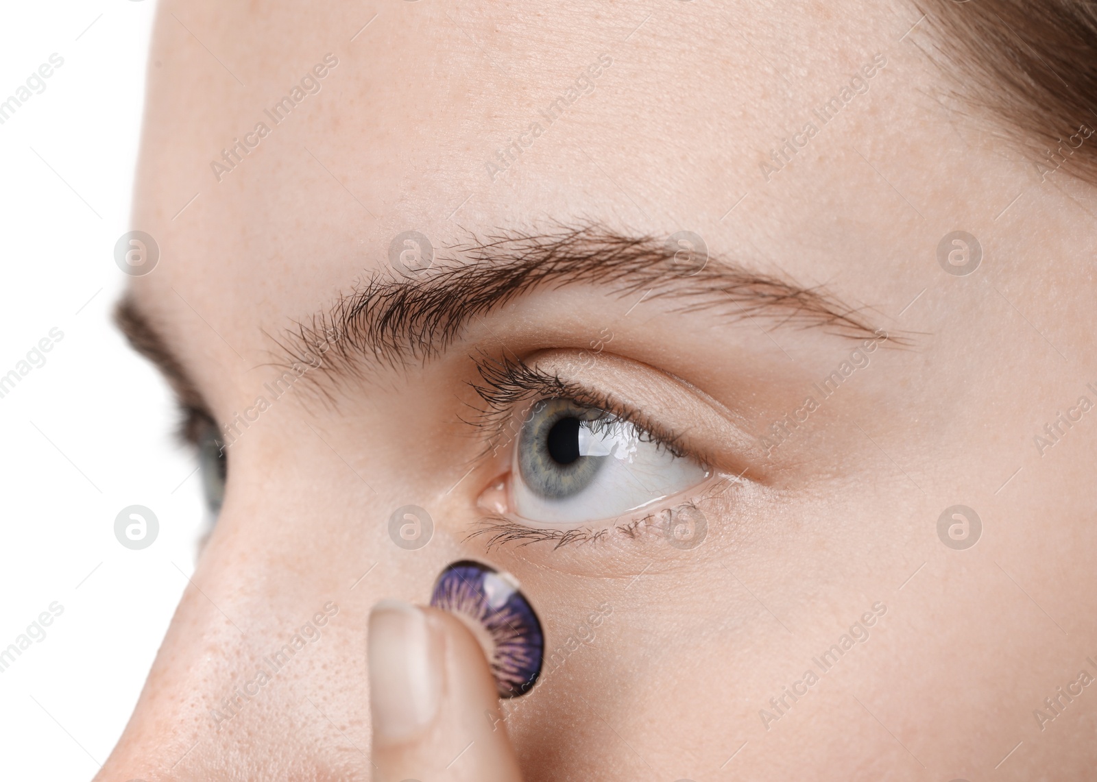 Photo of Woman putting in color contact lens on light background, closeup