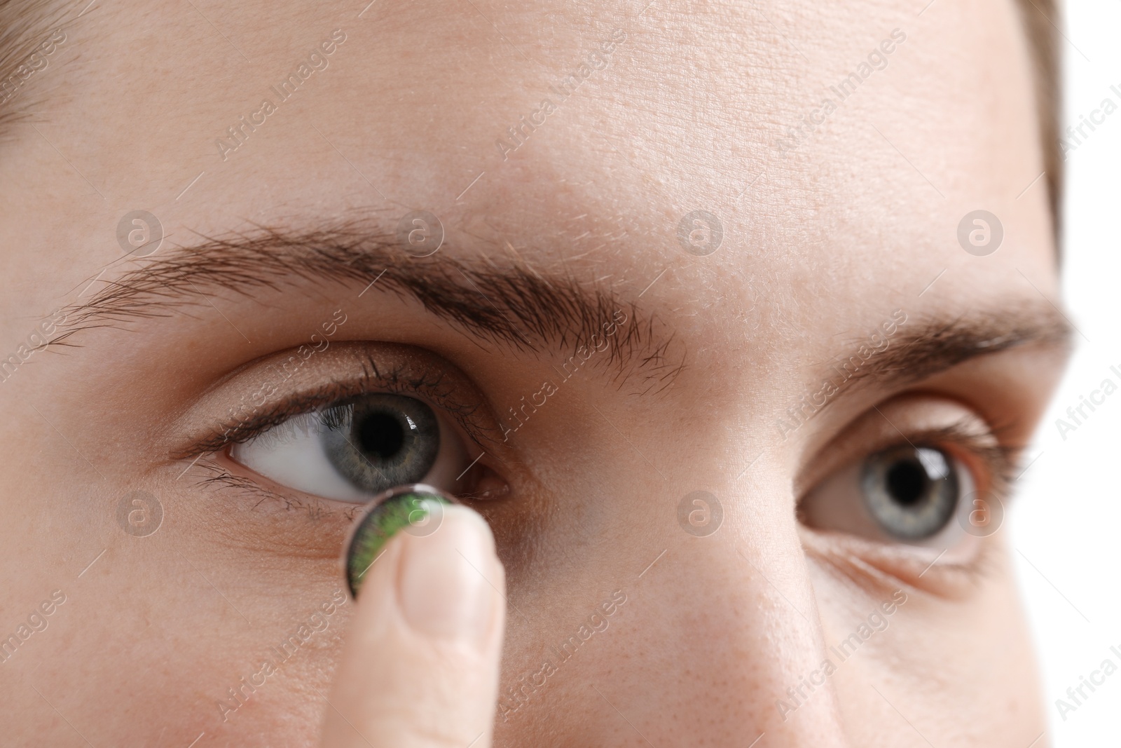 Photo of Woman putting in green color contact lens on grey background, closeup