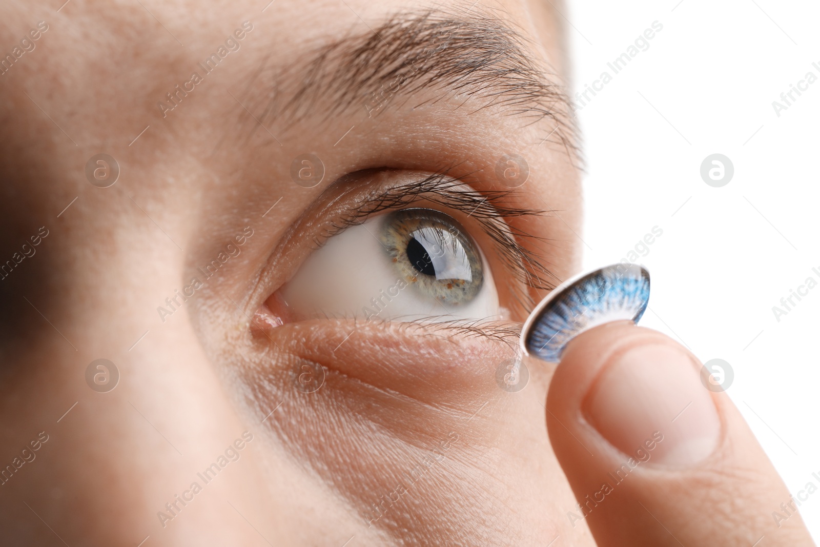 Photo of Man putting color contact lens in his eye on white background, closeup