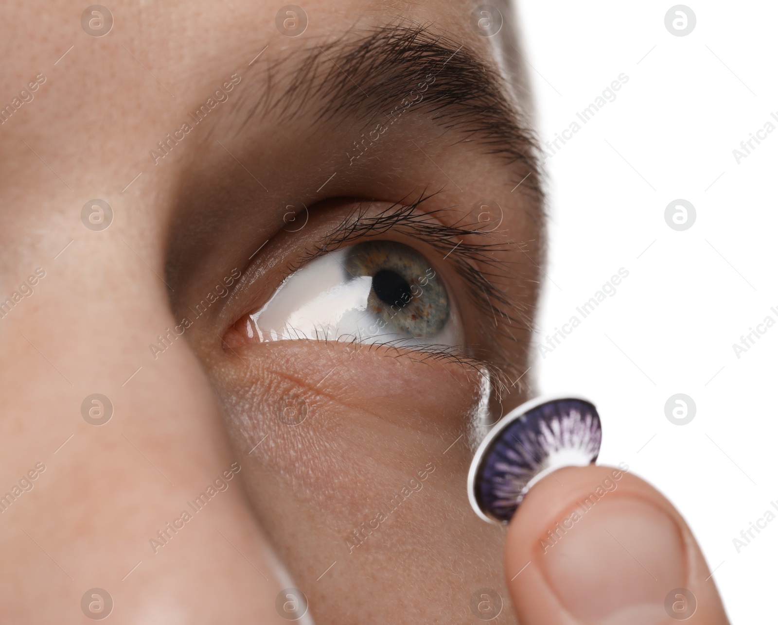 Photo of Man putting color contact lens in his eye on white background, closeup