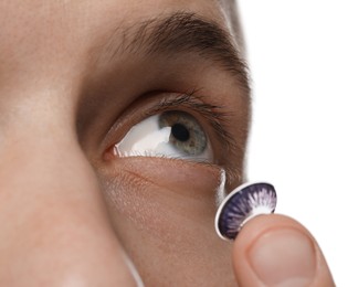 Photo of Man putting color contact lens in his eye on white background, closeup