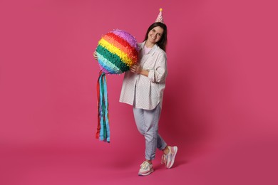 Photo of Happy woman with colorful pinata on pink background