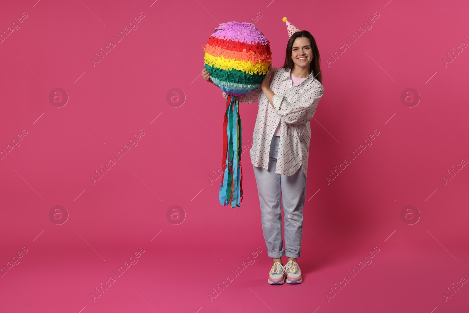 Photo of Happy woman with colorful pinata on pink background